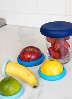 some fruit is sitting on the counter next to a blender with strawberries and lemons in it