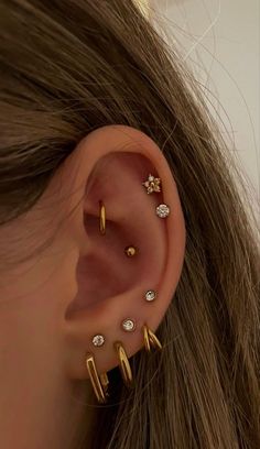 a woman with three different ear piercings on her left ear and one is gold