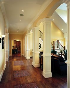 an open floor plan with wood floors and white columns