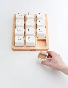 a person is holding a coffee cup next to a computer keyboard with the keys on it