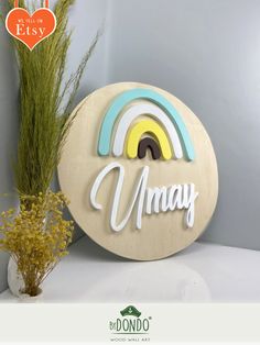 a wooden sign that says, mama with a rainbow in the middle and a plant next to it