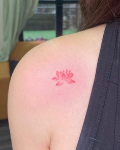 a woman's back shoulder with a pink lotus tattoo on it