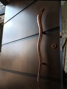 a door handle on the side of a brown cabinet in front of a stair case