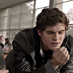 a young man in a leather jacket looking at something