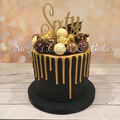 a black and gold birthday cake with chocolates on the top, drizzled in gold