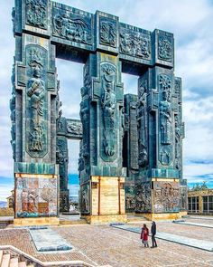 two people are standing in front of an intricately designed structure with statues on it