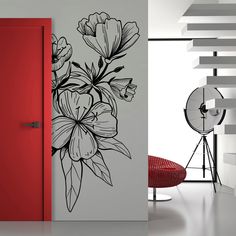 a red door is next to a white wall with flowers on it