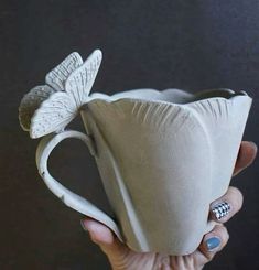 a hand holding a white coffee cup with a flower on it