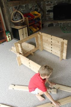 a young boy playing with wooden toys in front of a fire place on the floor