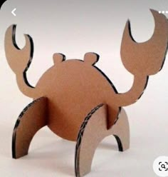 an animal made out of cardboard sitting on top of a white surface with the words cut out in front of it