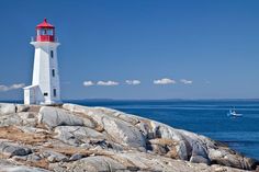 a white and red lighthouse sitting on top of a rocky shore