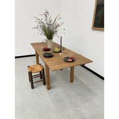 a wooden table with plates and bowls on it in front of a vase filled with flowers