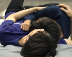 two people laying on top of each other with their heads touching one another's shoulders