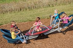 three children are playing on a small playground set in the dirt with two adults and one child