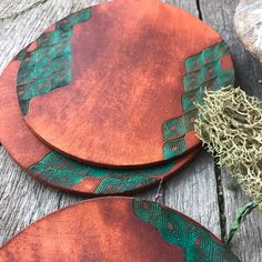 two wooden coasters with green designs on them