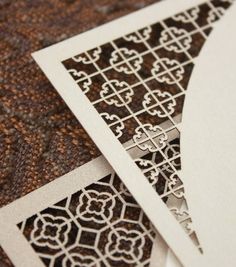 two cards with intricate designs on them sitting next to each other in front of a brown carpet