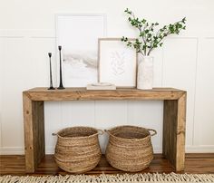 two baskets sitting on top of a wooden table next to a vase with flowers in it