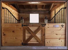 the inside of a horse barn with wooden walls and railings on either side of the door