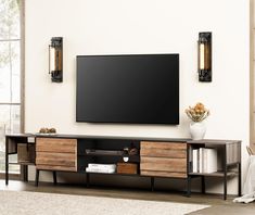 a large flat screen tv mounted to the side of a wooden entertainment center in a living room