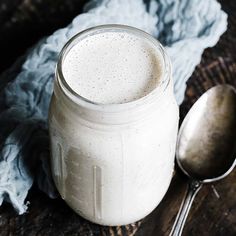 a glass jar filled with white liquid next to a spoon