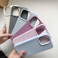 four different colored cases are stacked on top of each other in the shape of an iphone case