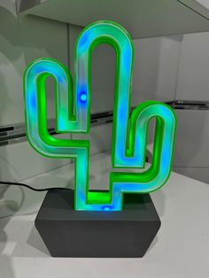 a green neon sign sitting on top of a black stand next to a white counter