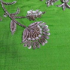 a green cloth with silver flowers and leaves on it