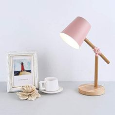 a pink lamp sitting on top of a table next to a cup and saucer