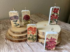 four small candles are sitting on top of a wooden stand with flowers painted on them