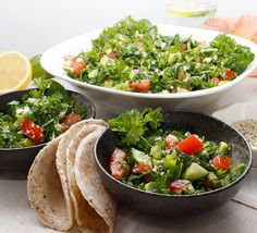 three bowls filled with salad and tortillas on top of a white table cloth