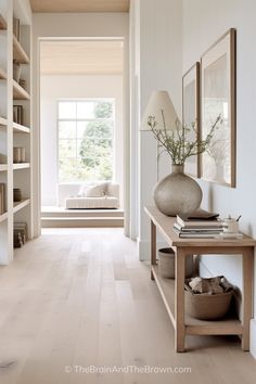 a room with white walls and wooden flooring in the center is filled with bookshelves