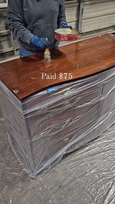 a man standing next to a large wooden chest with plastic covering on it's sides