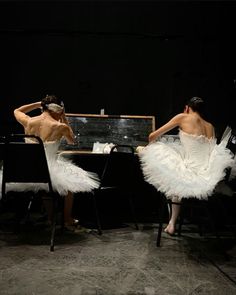 two people in white dresses sitting at a table