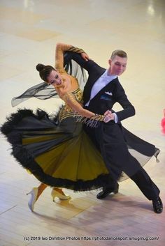 a man and woman in ballroom clothes dancing