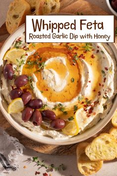 whipped feta with roasted garlic and honey in a white bowl surrounded by sliced lemons