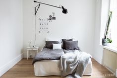 a bedroom with white walls and wood flooring is pictured in this image, the bed has two pillows on it