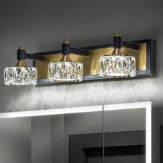 a bathroom vanity light with three lights on the top and one on the bottom, in front of a mirror