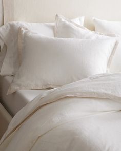 a bed with white linens and pillows on it