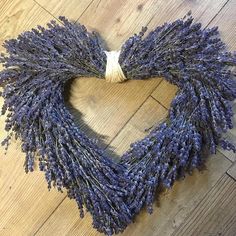 a heart shaped wreath made out of lavenders on a wooden floor with twine