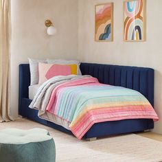 a bed with colorful blankets and pillows in a room next to a painting on the wall