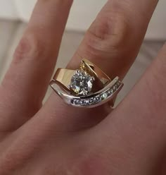 a woman's hand with a gold and white diamond ring on top of her finger