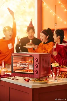 three people are celebrating with coca - cola on the kitchen counter and in the background is a christmas tree