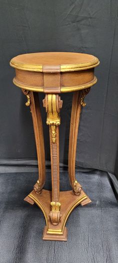 an antique wooden table with gold trimmings and carvings on the top, sitting against a black background