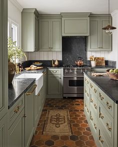 a kitchen with green cabinets and black counter tops, an area rug on the floor