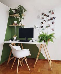 a desk with two chairs and a computer on top of it in front of a green wall