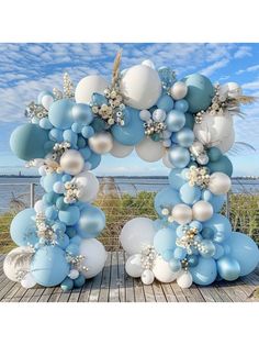 blue and white balloons are arranged in the shape of an arch on a wooden table