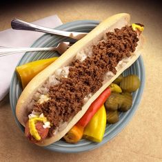 a hot dog on a plate with peppers and pickles