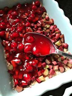 a spoon is sitting in a dish filled with cherries and rhubarb