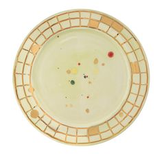 a white plate with gold and red dots on the rim, against a white background