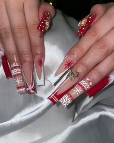 These long square nails showcase a bold red and white pattern with holiday details like snowflakes and knit textures. A gold bow accent on one nail adds a festive touch, making it perfect for the holidays. This look is great for those who love detailed and playful sweater art designs. Christmas Nails Dramatic, Christmas Nails Decor Ideas, Xmas Nails With Bow, Red Christmas Sweater Nails, Cute Long Christmas Nails, Christmas Long Nail Designs, Red Bling Christmas Nails, Red And Gold Christmas Nails Acrylic, Winter Nails Long Square